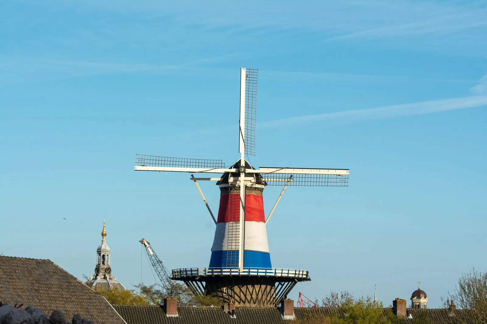 Dutch windmill wrapped in red, white and blue, the colours of the Dutch flag, against a blue sky