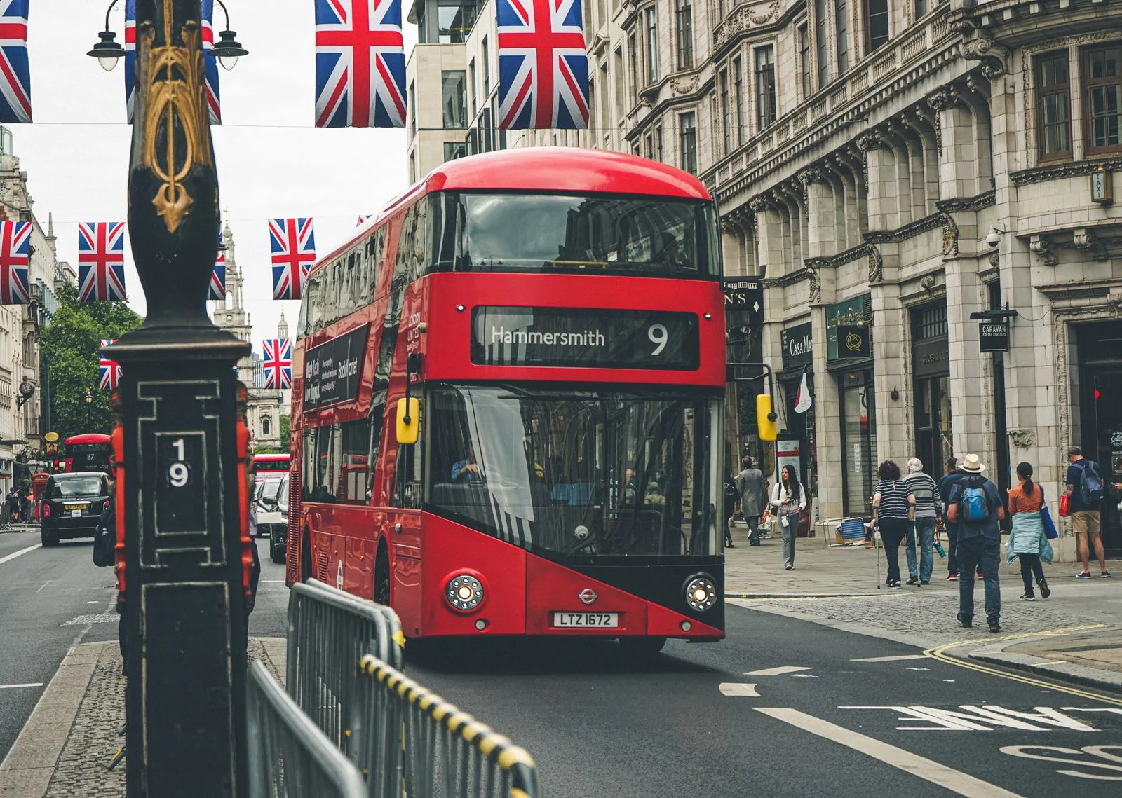 Red double-decker London bus on a street hung with Union Jack flags
