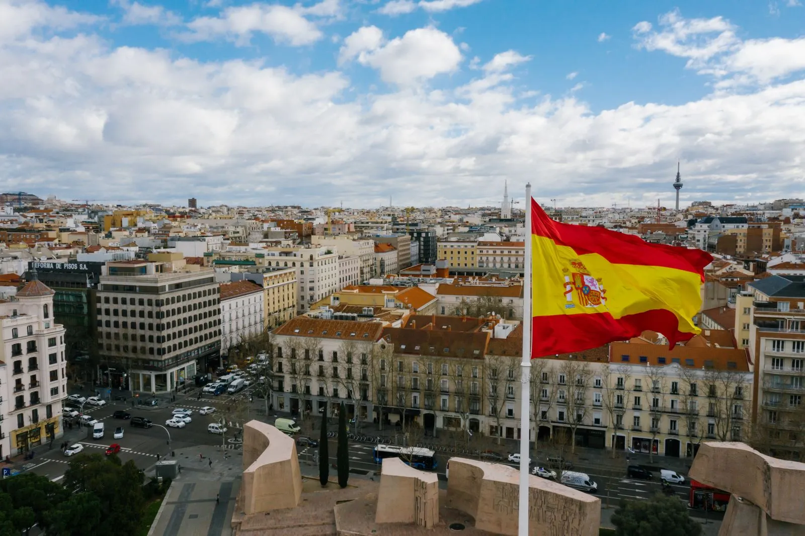 Spanish flag flying over the rooftops of Madrid on a cloudy day