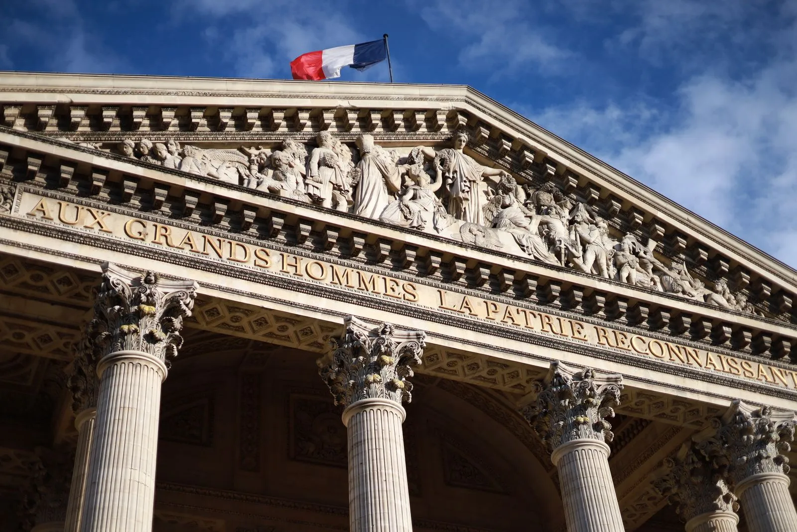 French flag above the pediment of the Panthéon in Paris, with the inscription “Aux grands hommes la patrie reconnaissante”